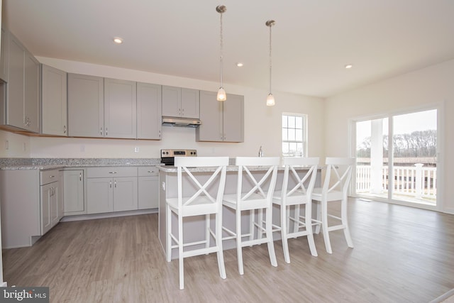 kitchen with gray cabinetry, decorative light fixtures, a kitchen island, and light hardwood / wood-style flooring