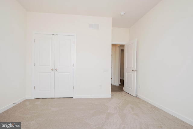 unfurnished bedroom featuring light colored carpet and a closet