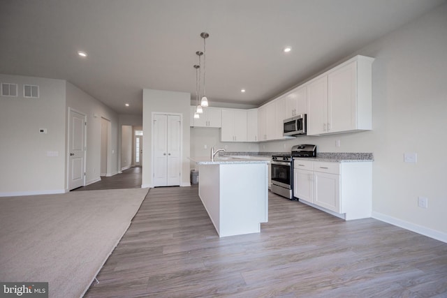 kitchen featuring white cabinets, appliances with stainless steel finishes, and a center island with sink