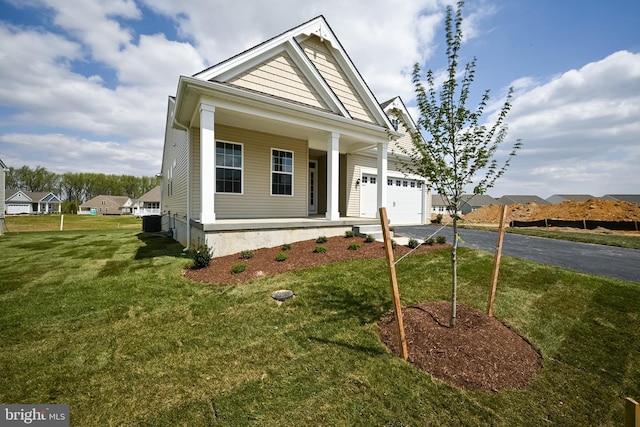 view of front of home featuring a garage, covered porch, and a front lawn