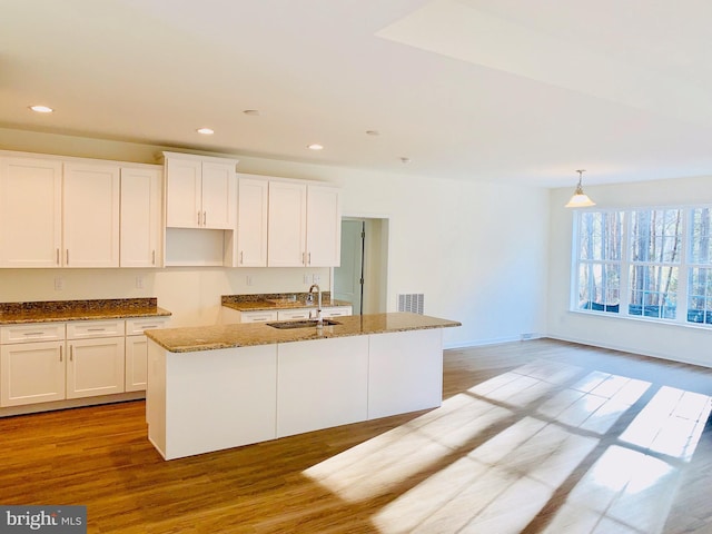 kitchen featuring a center island with sink, white cabinetry, and light hardwood / wood-style flooring