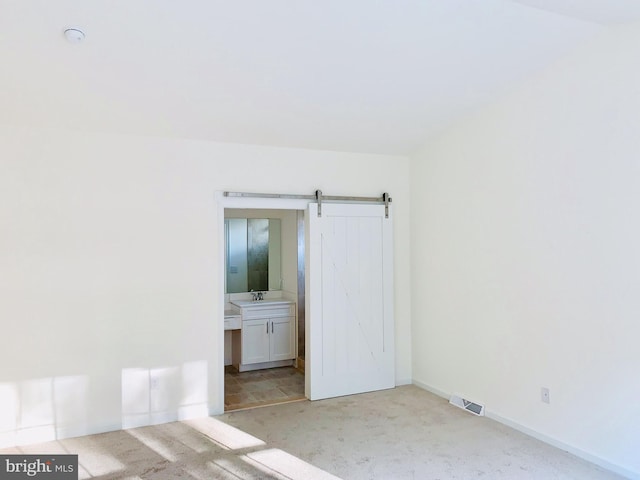 carpeted spare room with a barn door and sink