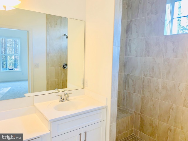 bathroom featuring plenty of natural light, vanity, and tiled shower