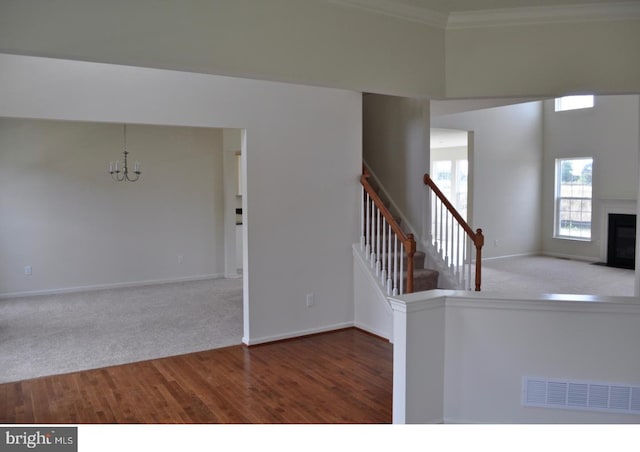 foyer entrance with hardwood / wood-style floors, crown molding, and a notable chandelier