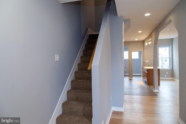 stairway with wood finished floors and recessed lighting