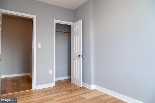 unfurnished bedroom featuring light wood-style flooring and a closet