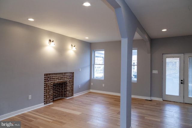 unfurnished living room featuring light wood finished floors, a fireplace, recessed lighting, and french doors