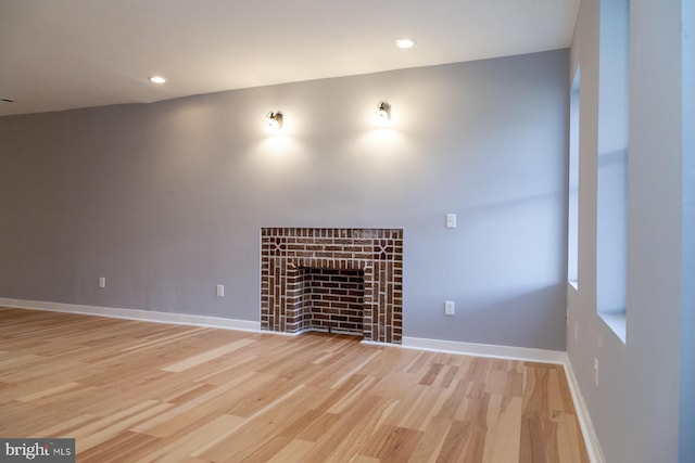 unfurnished living room with light wood-type flooring, a tiled fireplace, and recessed lighting