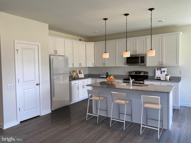 kitchen featuring a kitchen breakfast bar, a center island with sink, dark hardwood / wood-style floors, and appliances with stainless steel finishes