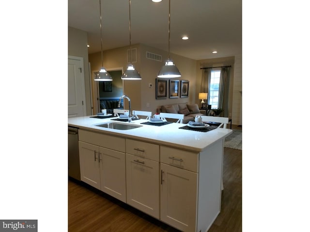 kitchen with dark wood-type flooring, sink, pendant lighting, a center island with sink, and white cabinets