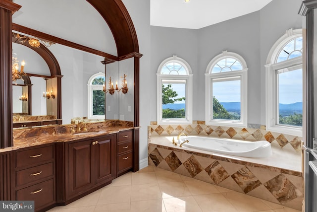 bathroom featuring tiled tub, vanity, and tile patterned flooring