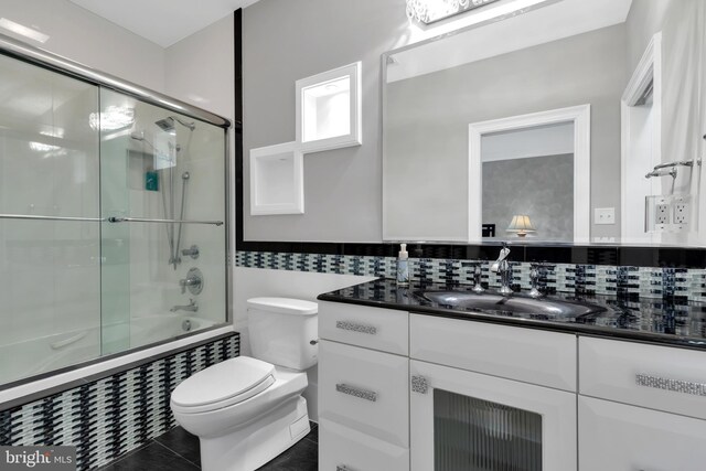 full bathroom with decorative backsplash, toilet, vanity, tile patterned flooring, and enclosed tub / shower combo