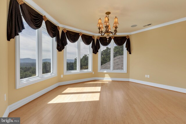 unfurnished dining area featuring light hardwood / wood-style flooring, crown molding, and a notable chandelier