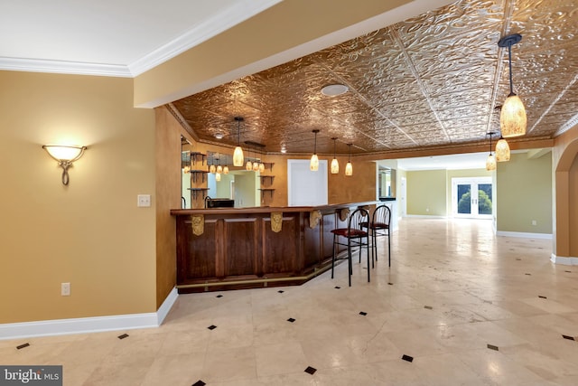 interior space featuring tile patterned floors, a breakfast bar, pendant lighting, and ornamental molding