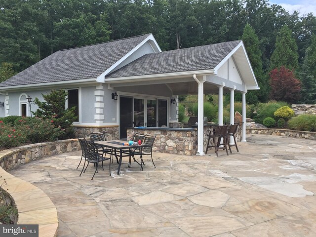 view of patio with an outdoor bar and a grill