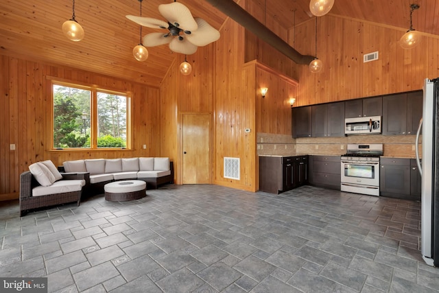 kitchen with hanging light fixtures, appliances with stainless steel finishes, high vaulted ceiling, ceiling fan, and dark tile patterned floors