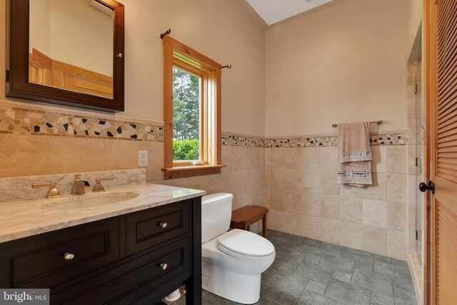 bathroom featuring tile patterned floors, vanity, tile walls, and toilet