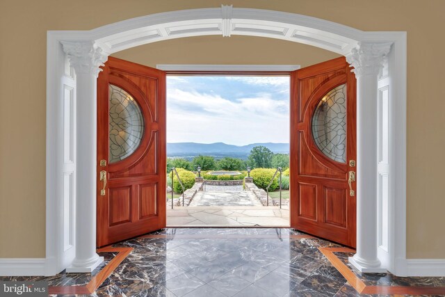 tiled entryway with a mountain view, a wealth of natural light, and ornate columns