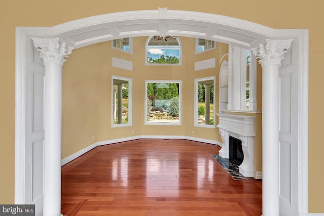 interior space featuring decorative columns, a premium fireplace, and hardwood / wood-style floors