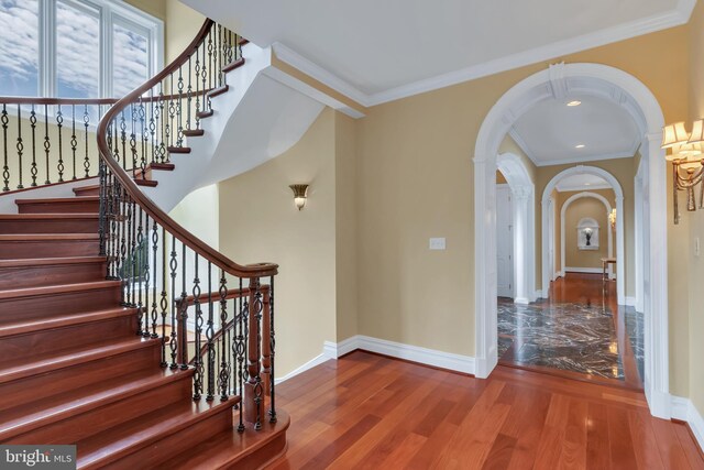 stairs with ornamental molding and hardwood / wood-style floors