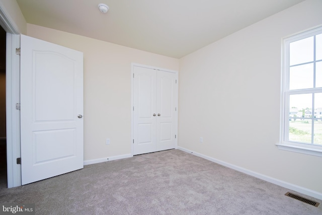 unfurnished bedroom with a closet and light colored carpet