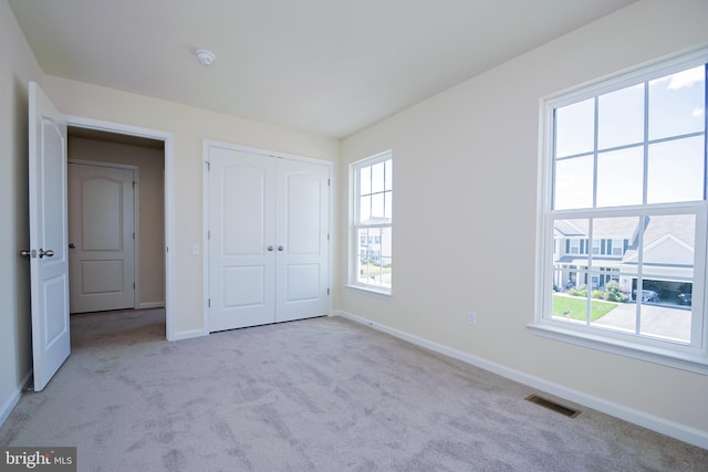 unfurnished bedroom featuring light colored carpet and a closet