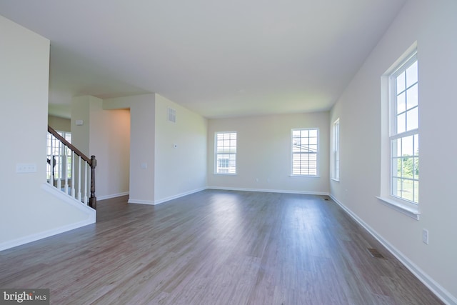 unfurnished living room featuring dark hardwood / wood-style floors and a wealth of natural light