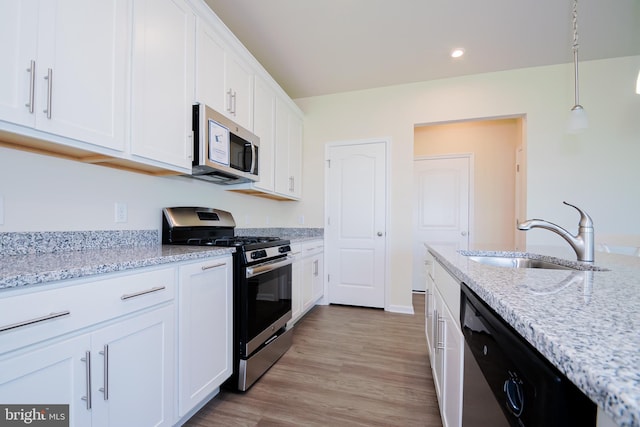 kitchen with sink, light wood-type flooring, stainless steel appliances, white cabinets, and light stone counters