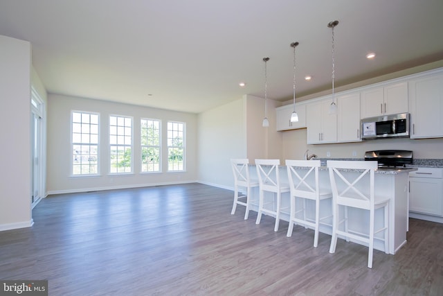 kitchen featuring dark hardwood / wood-style flooring, range, a kitchen breakfast bar, and a kitchen island with sink