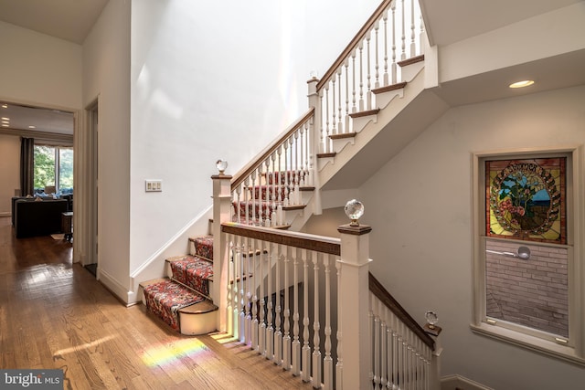 staircase featuring wood-type flooring and a towering ceiling