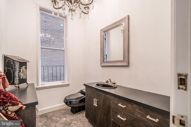 bathroom featuring vanity, an inviting chandelier, and toilet