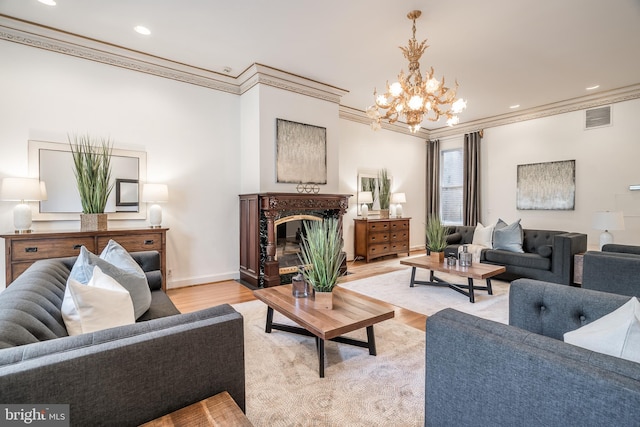 living room with a chandelier, ornamental molding, and light hardwood / wood-style flooring