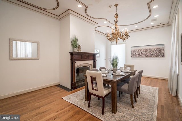 dining room with an inviting chandelier, light hardwood / wood-style flooring, and ornamental molding