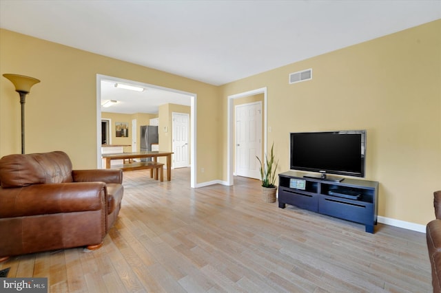 living area featuring baseboards, visible vents, and wood finished floors
