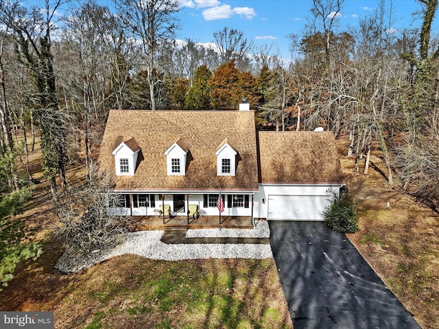 new england style home with a chimney, a shingled roof, driveway, and an attached garage