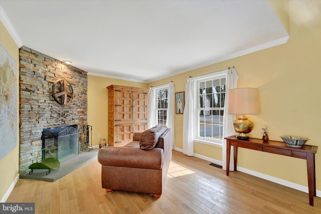 living area with crown molding, visible vents, hardwood / wood-style floors, baseboards, and a fireplace