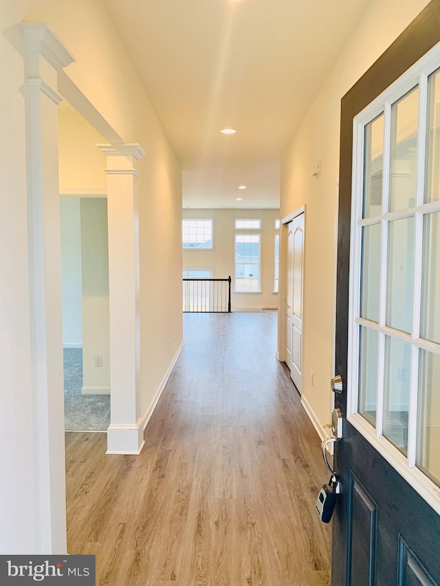 hall with ornate columns and light hardwood / wood-style floors