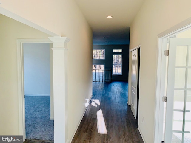 hallway with dark hardwood / wood-style floors and ornate columns