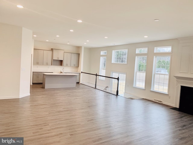 unfurnished living room with sink and light wood-type flooring