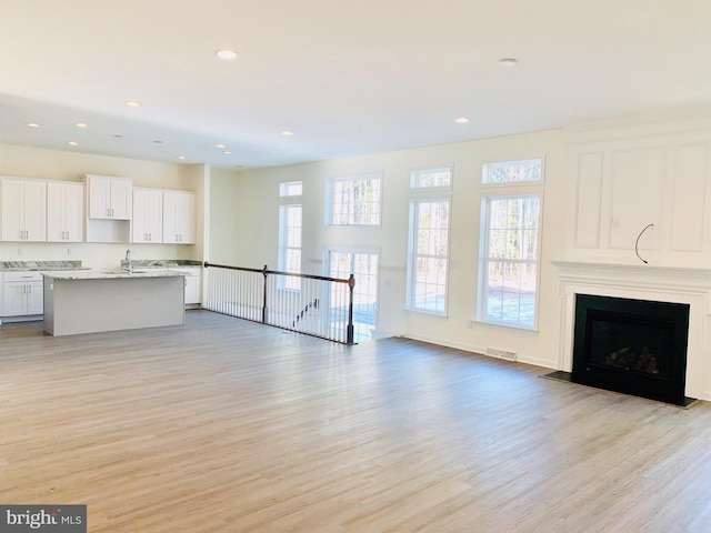 unfurnished living room with light hardwood / wood-style flooring and sink