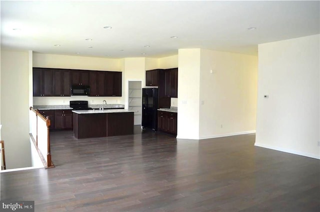 kitchen featuring dark hardwood / wood-style flooring, dark brown cabinets, sink, black appliances, and a center island with sink