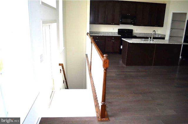 kitchen with sink, light stone counters, dark hardwood / wood-style floors, dark brown cabinets, and black appliances