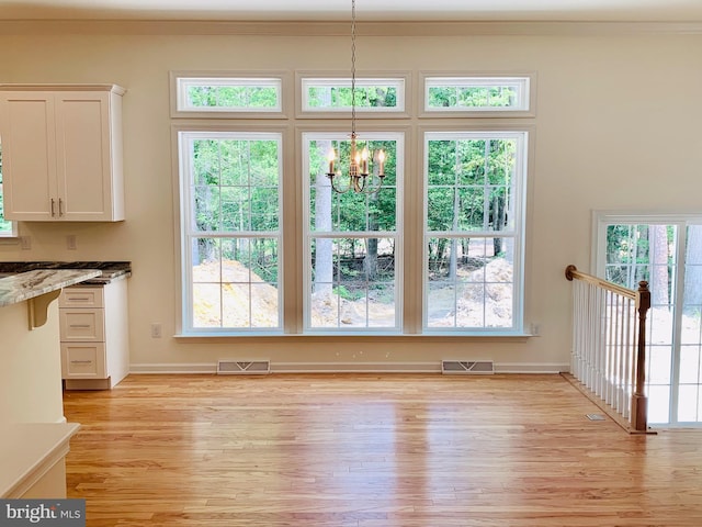 unfurnished dining area featuring an inviting chandelier and light hardwood / wood-style floors