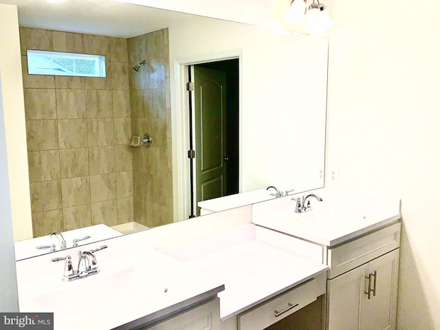 bathroom with tiled shower and vanity