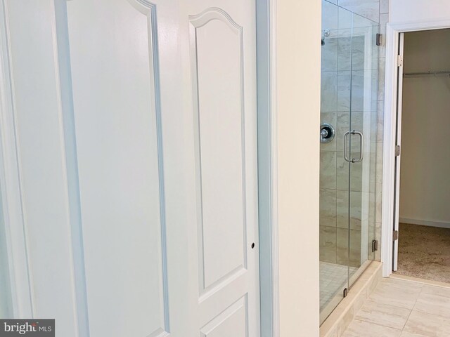 bathroom with a shower with shower door and tile patterned flooring