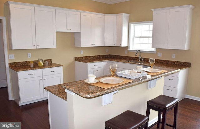 kitchen featuring white cabinets, sink, a breakfast bar area, and dark hardwood / wood-style flooring