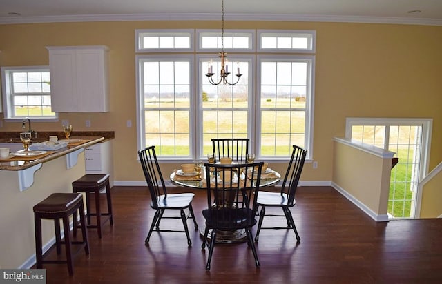 dining area featuring a notable chandelier, dark wood-type flooring, plenty of natural light, and crown molding