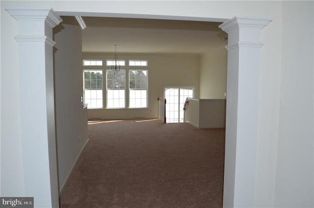 unfurnished room with decorative columns, carpet flooring, ornamental molding, and an inviting chandelier