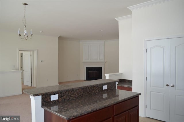 kitchen featuring an inviting chandelier, light carpet, dark stone countertops, hanging light fixtures, and a center island