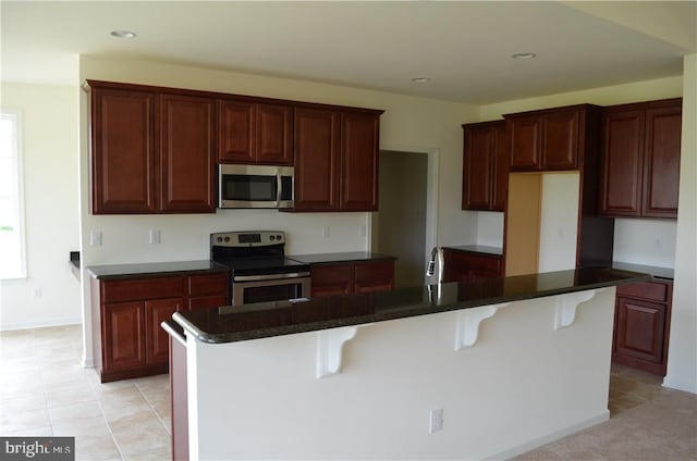 kitchen with a breakfast bar, stainless steel appliances, a healthy amount of sunlight, and an island with sink